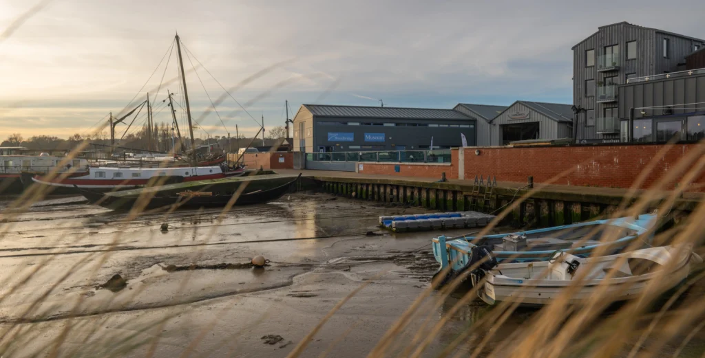Woodbridge museum seem across muddy river on grey day