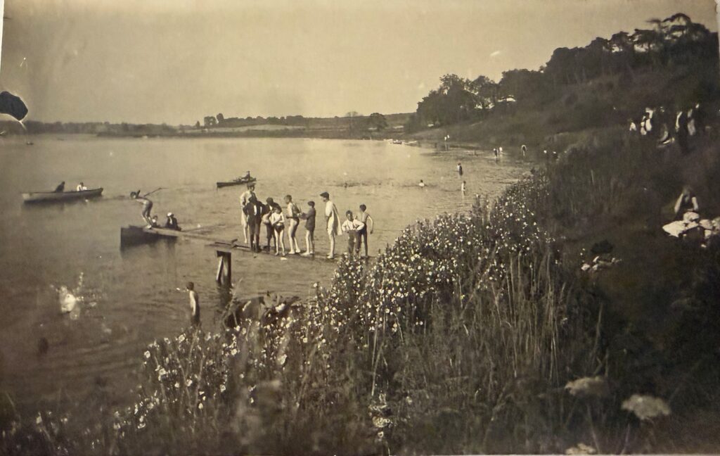 People lined up on a board jetting out onto the river, with other paddling in the distance